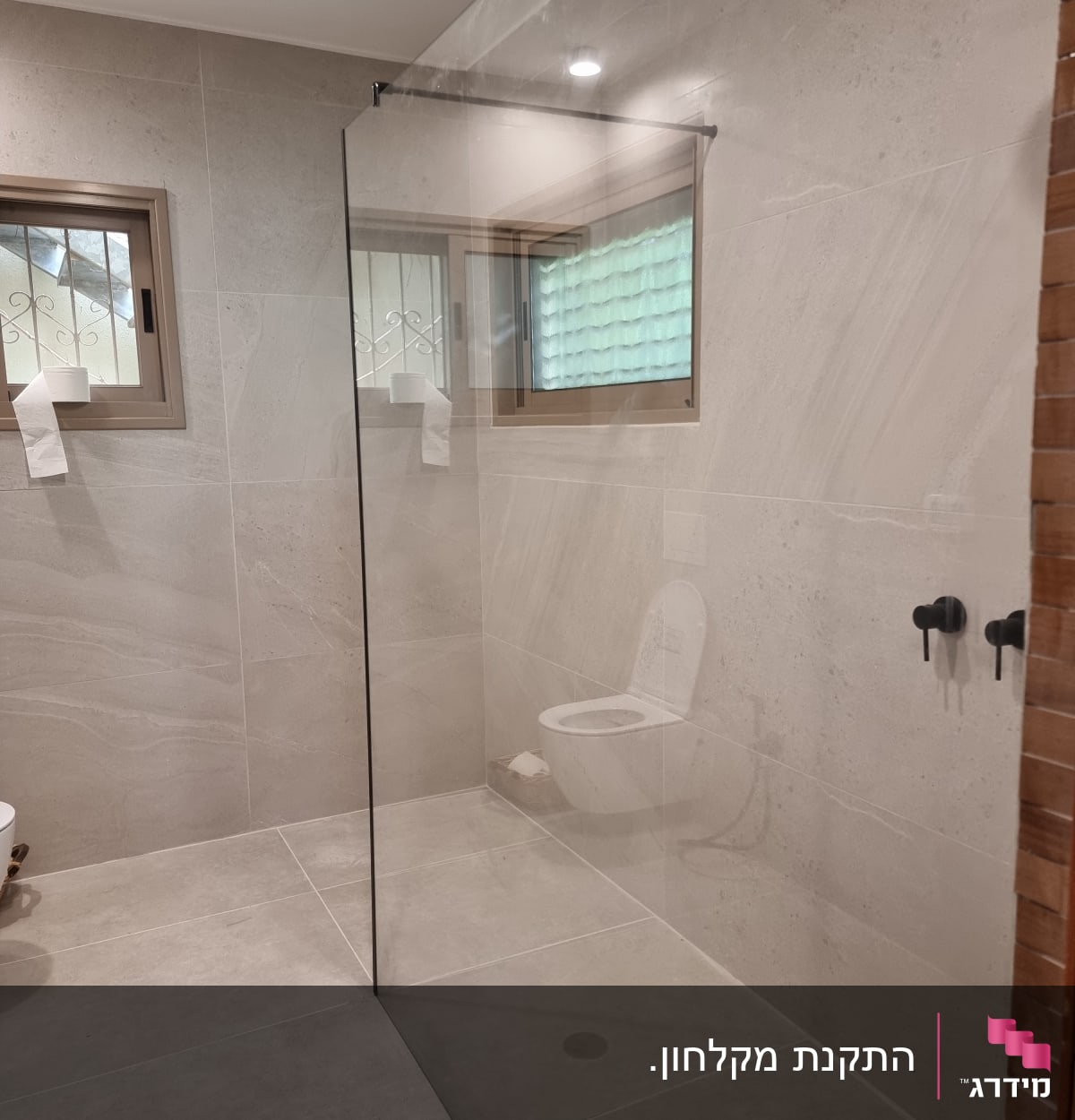 מחיצת זכוכית במקלחת עם ראש מקלחת שחור